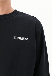 Black sweatshirt made of soft fabric, featuring a ribbed crew neckline and a prominent white logo on the chest. Simple design and ample fit.
