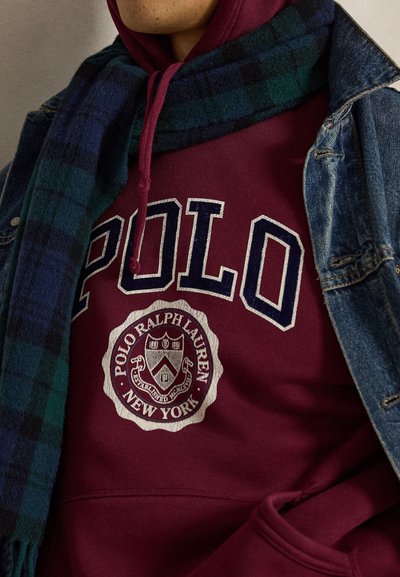 Άτομο που φοράει μαρόν φούτερ Polo Ralph Lauren με μπλε και πράσινο καρό κασκόλ και τζιν μπουφάν.