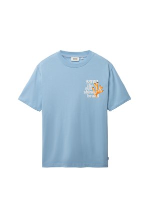 Camiseta de manga corta azul claro con un pequeño gráfico de coral naranja y texto blanco en el pecho izquierdo que dice "SHIWI the sun shine brand."