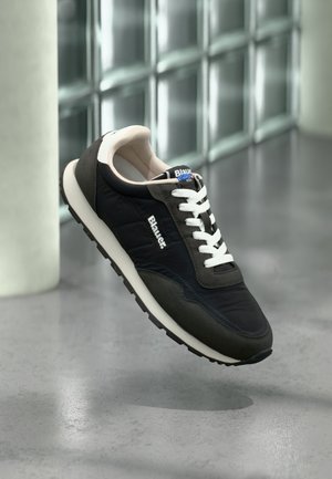 Baskets noires et grises avec une tige texturée, des lacets blancs et une semelle crème. Présentent un logo sur le côté et un col rembourré pour le confort.