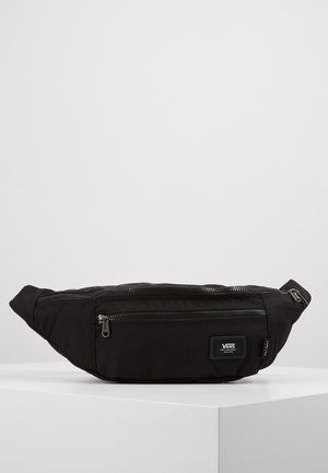 Sac banane noir Vans avec deux compartiments zippés et écusson logo, présenté sur une surface blanche sur fond uni.