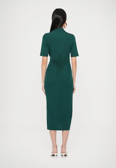 Zelené ľahko priliehajúce šaty po kolená s krátkymi rukávmi, s vyformovaným pásom a nariasenými detailmi vzadu. Hladká látka so štýlovou siluetou.
