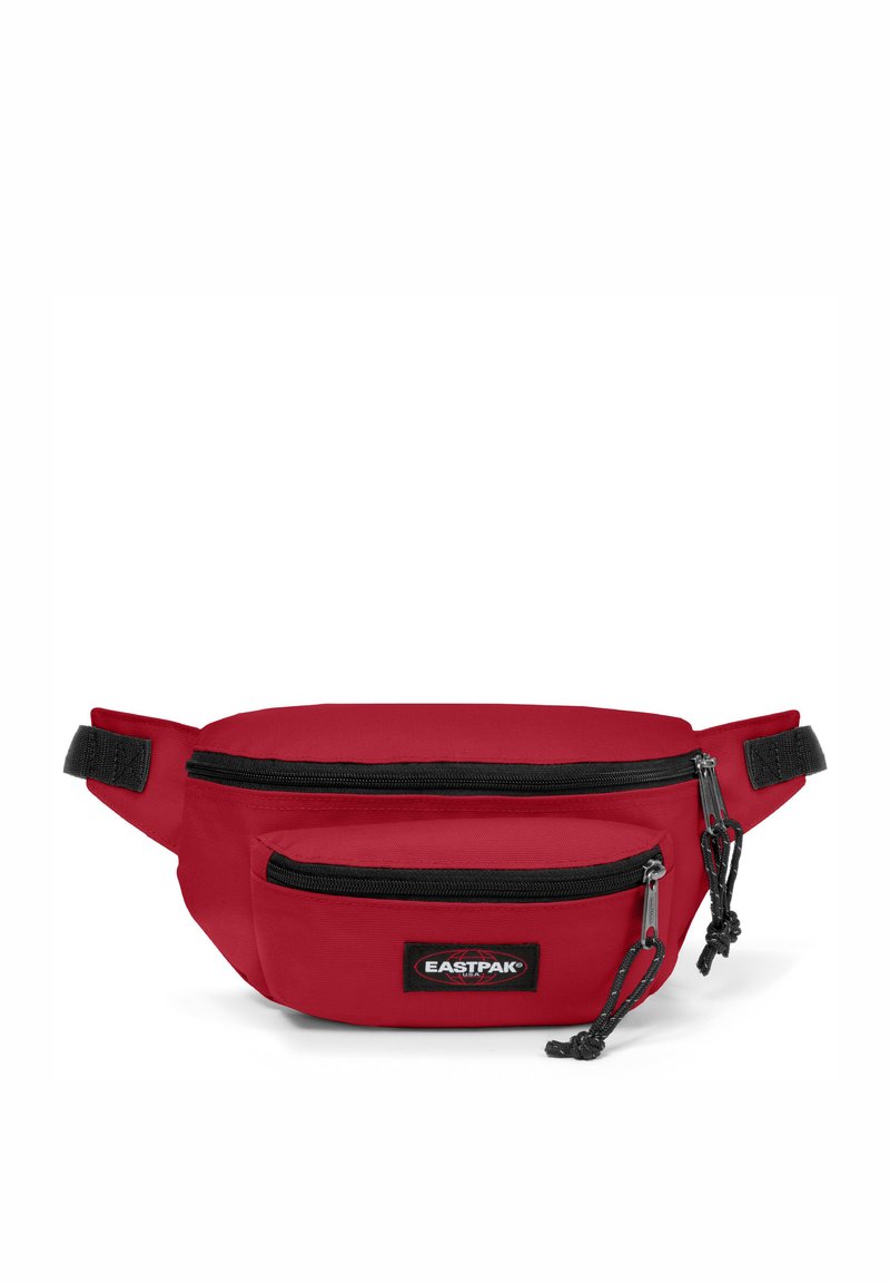 Červená látková ledvinka s dvěma zipovými kapsami, černými zipovými akcenty a logem Eastpak. Obdélníkový tvar, nastavitelné úchyty.
