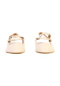 Chaussures plates beiges pour femmes, à bouts ronds et à doubles brides de cheville avec petites boucles dorées, présentées de face sur fond blanc.