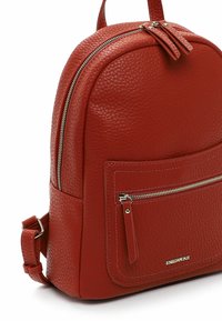 Roter, genarbter Leder-Rucksack mit runder Form. Verfügt über eine vordere Reißverschlusstasche, doppelte Reißverschlüsse und einen oberen Griff zum Tragen.