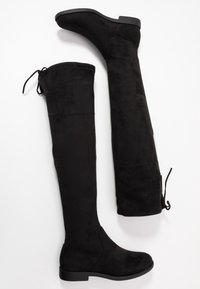 Botas negras sobre la rodilla hechas de suave gamuza, con una silueta esbelta, punta redondeada y un tacón bajo y cuadrado con un detalle de lazo.