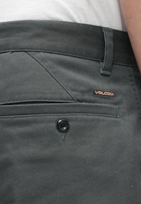 Σκούρο γκρι παντελόνι Volcom με υφή υφάσματος, εμφανές κουμπί, πλαϊνή τσέπη και ραμμένες λεπτομέρειες κοντά στη μέση.