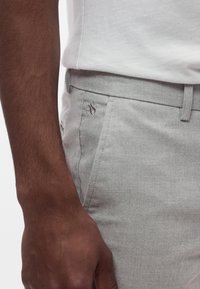 Ανοιχτόγκρι υφασμάτινο παντελόνι με στενή εφαρμογή και διακριτικό σχέδιο στο ύφασμα. Διαθέτει διακριτικό λογότυπο στην αριστερή τσέπη και επίπεδη μέση.