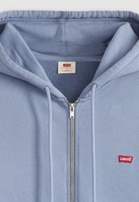 Lichtblauwe rits hoodie van een katoenmix, met een klein rood Levi's logo op de linkerkant van de borst en een trekkoord voor de capuchon.