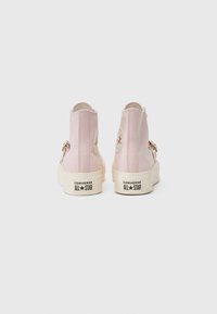 Adidași roz cu glezna înaltă, având o talpă din cauciuc, vârf rotund și logo-ul iconic cu stea pe lateral. Material texturat cu accente albe în contrast.