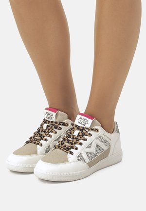 Baskets blanches avec des lacets imprimés léopard et des accents gris, présentant un panneau latéral pailleté et une étiquette de logo rose au talon. Matériaux texturés.