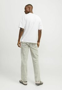 Tricou alb cu maneci scurte, cu o croială lejeră, asortat cu blugi deschis la culoare, decolorati, cu croială dreaptă și detalii de cusătură subtile.