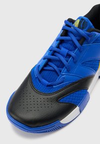 Blue athletic shoe with a black leather toe cap, textured blue mesh, and perforations for ventilation. Features blue laces and a logo.