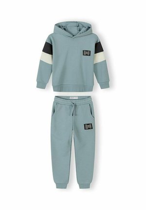 Svetlomodra jopa s kapuco in ujemajoče se hlače jogger s črnimi in belimi črtami na rokavih ter črnimi obliži z napisom "Unlimited Collective".