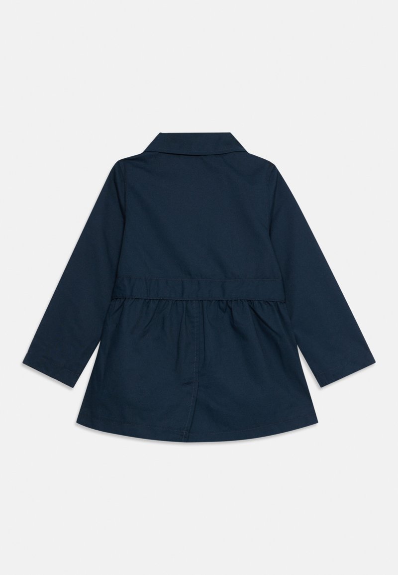 Manteau bleu marine à manches longues, avec un col et une taille froncée. Fabriqué en tissu lisse avec un design simple et classique.