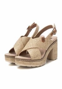 Sandalias de tiras cruzadas en color beige con textura trenzada, tacón grueso y hebilla ajustable. Plantilla acolchada y suela de goma.
