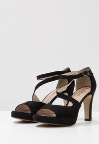 Svarta suède högklackade sandaler med korsande remmar, öppen tå och plattformssula, med en jämn beige foder och spänne.