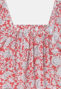 Tessuto rosso con motivo floreale bianco, arricciatura elastica raccoglie il collo e la parte superiore del corpo di un indumento.