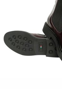 Stivale in pelle alla caviglia con tomaia bordeaux, dotato di suola in gomma nera testurizzata con motivi di presa circolari e etichetta con logo. Taglia 37.