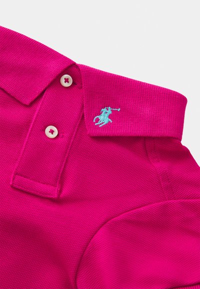Cuello de polo de color rosa brillante con dos botones blancos y pequeño logo bordado de un jugador de polo en turquesa en el cuello.