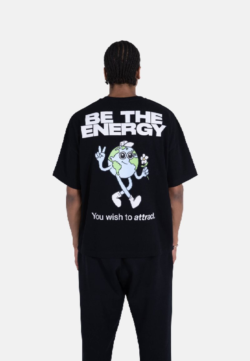 Svart oversized t-skjorte med et livlig grafisk motiv av en tegneserie-jordklode som holder en blomst, med fet tekst over og under designet.
