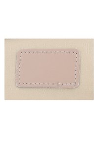 Beige tyg med en slät ljusrosa läderlapp, kantad med vit söm. Texturen är mjuk och lappen är centrerad.