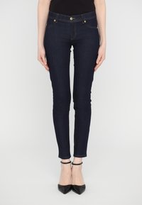 Mörkblå skinny jeans i denim, med en klassisk femficksdesign, guldstickning och en dragkedja med knapp i överkant.