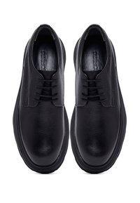 Chaussures en cuir noir à lacets avec une finition texturée et un bout arrondi, dotées d'une doublure lisse et d'une semelle en caoutchouc noir.