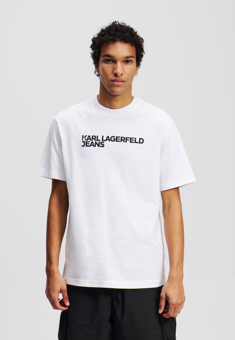 Weißes Baumwoll-T-Shirt mit dem Aufdruck "KARL LAGERFELD JEANS" in fetten schwarzen Buchstaben auf der Vorderseite. Kurze Ärmel und Rundhals-Ausschnitt.