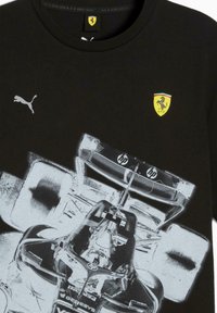 Sort t-shirt med en hvid grafisk fremstilling af en Ferrari racerbils, Puma logo og Ferrari emblem på brystet.