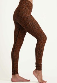 Åtsittande leggings i ett svart och orange mönster, med hög midja och samlade anklar för en texturerad look.