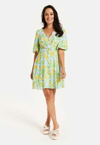 Floral dress featuring a light blue background, yellow and green leaf patterns, short puff sleeves, a v-neck, and a cinched waist design.