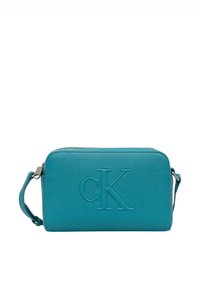 Sac bandoulière en cuir turquoise avec logo "CK" embossé, fermeture éclair et bandoulière réglable. Texture lisse et forme rectangulaire.
