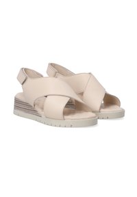 Beige leather sandals with crossover straps, slingback design, textured insole, and a wedge heel with horizontal stripes.