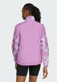 Lätt, lavendelfärgad jacka med geometriskt mönstrade ärmar, hög krage och elastiska muddar. Den har en avslappnad passform och en mjuk textur.