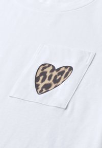 T-shirt blanc avec une poche poitrine carrée décorée d'un cœur à imprimé léopard centré sur la poche.