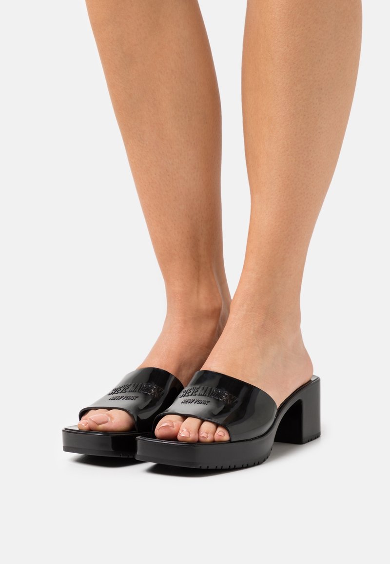 Sandales à enfiler en cuir verni noir avec un talon bloc épais, dotées d'une large bride et d'un logo embossé sur la partie supérieure.