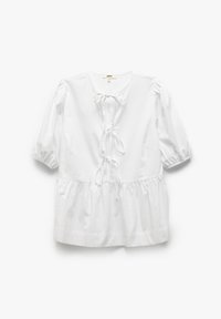Blouse blanche avec des manches courtes bouffantes, un col rond et une taille cintrée. Présente une fermeture à nœud à l'avant et un ourlet froncé.