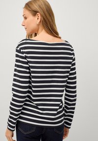 Langsleeve top in zwart-witte horizontale strepen, gemaakt van zachte stof met een brede halslijn en een relaxte pasvorm. Geen zichtbare metalen onderdelen of patronen.
