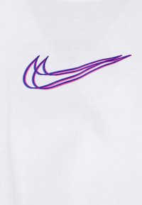 White cotton t-shirt featuring a Nike logo in blue and pink, characterized by smooth texture and minimalistic design.