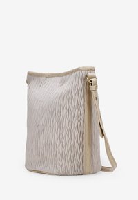 Bolso en material texturizado de color beige claro, con un patrón trenzado, ribete suave en color crema y una correa para el hombro ajustable.