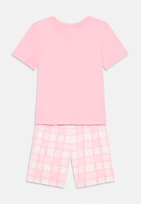 Camiseta de algodón rosa con mangas cortas combinada con pantalones cortos de cuadros rosa. Ambas prendas tienen una textura suave y un diseño casual.