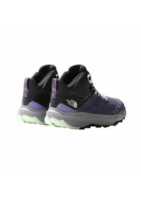 Para fioletowych i czarnych wysokich butów trekkingowych z grubymi szarymi podeszwami, jasnoszarymi sznurówkami i logiem The North Face z boku.