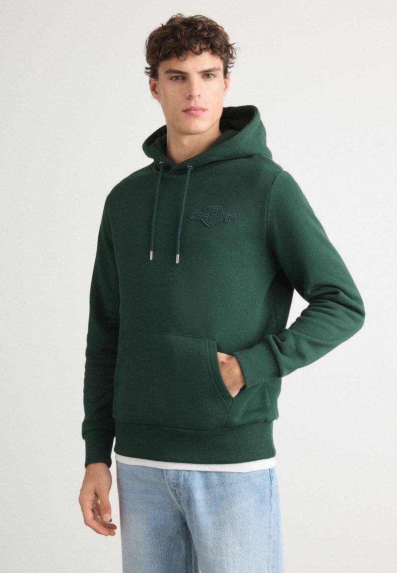 Felpa verde con cappuccio realizzata in cotone, dotata di tasca frontale, polsini a coste e logo ricamato sul petto di un verde più scuro.