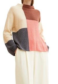 Gruby sweter dziany o wysokim kołnierzu, z blokami kolorów w odcieniach beżu, brązu, szarości i różu. Prążkowana faktura i szerokie rękawy.