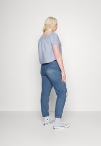 T-Shirt de algod�ão com decote ombro a ombro, com riscas azuis e brancas, combinado com jeans azuis desgastados e ténis de cano alto azul claro.