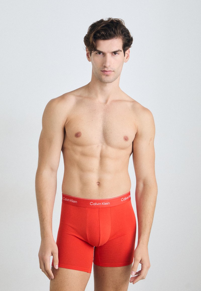 Boxers en coton rouge avec un design ajusté, dotés d'une large ceinture de marque Calvin Klein et d'une texture lisse.