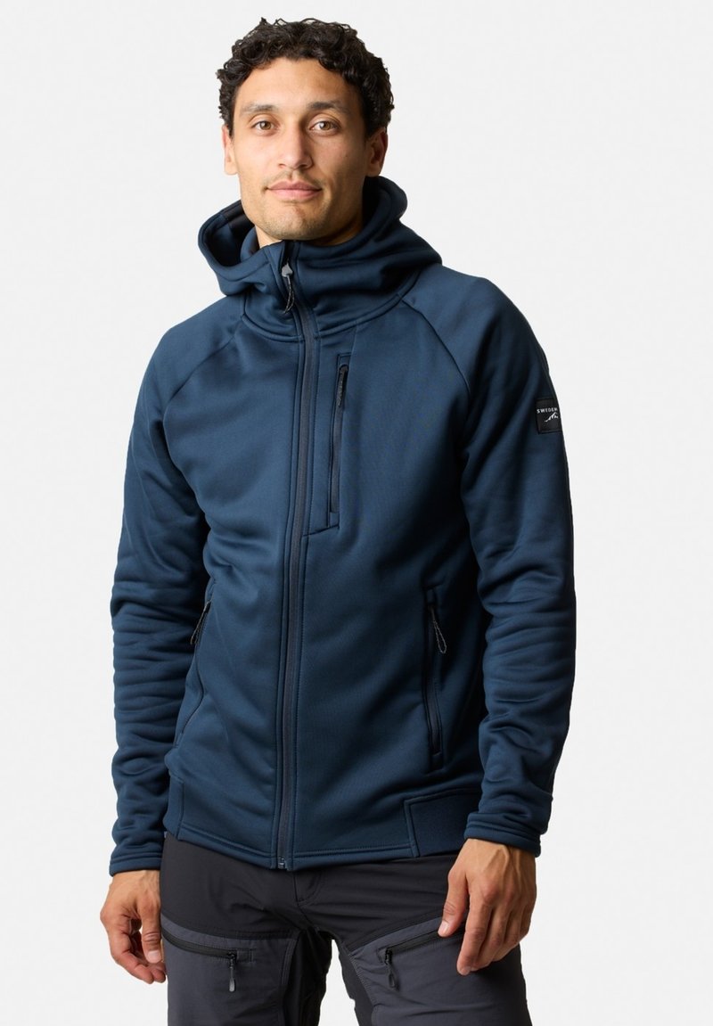 Felpa blu navy con zip completa, tasche laterali e taschino sul petto. Caratterizzata da un alto collare e un tessuto morbido con leggera elasticità.