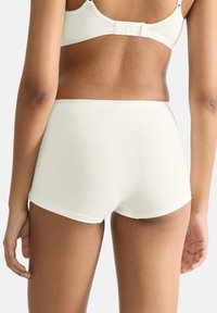 Sous-vêtements en coton blanc avec une texture lisse. Design taille haute avec des bords doux, arborant un style minimaliste et un dos sans coutures.