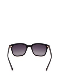 Lunettes de soleil carrées noires avec verres foncés dégradés et branches fines, vues de face sur fond blanc.